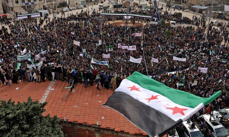 أعلام الثورة ترفرف في إدلب.. آلاف المتظاهرين يجددون العهد مطالبين بإسقاط الأسد